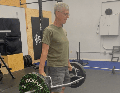 An elderly man lifting weights at a gym