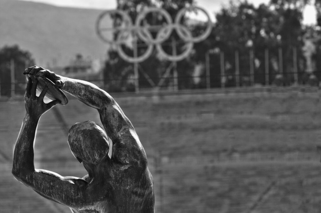 An Olympic statue in from of the Olympic rings